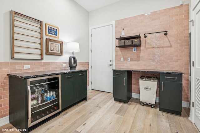 kitchen featuring dark stone counters, wine cooler, and light hardwood / wood-style flooring