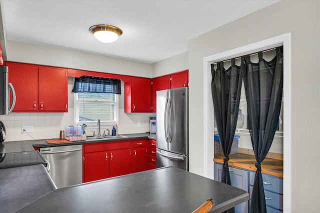 kitchen with a textured ceiling, decorative backsplash, sink, and appliances with stainless steel finishes