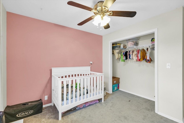 carpeted bedroom with a crib, a closet, and ceiling fan