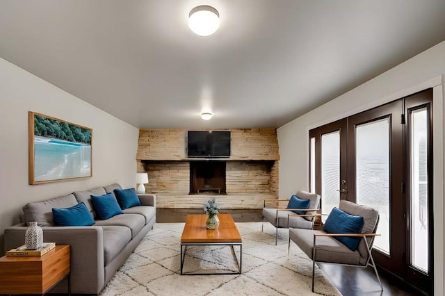 living room featuring french doors, a stone fireplace, and wood-type flooring