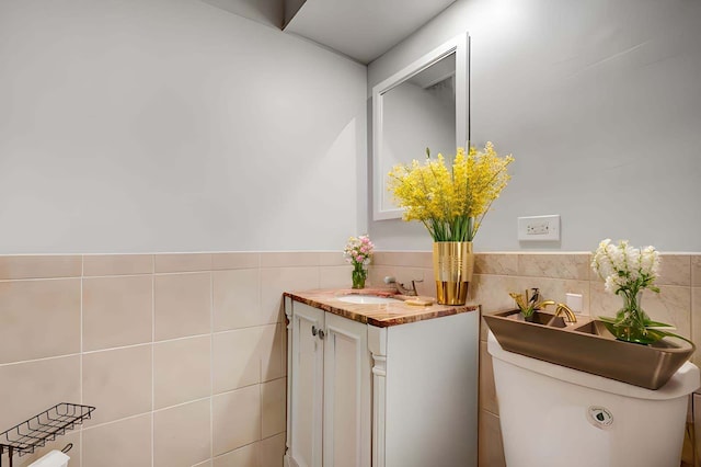 bathroom with vanity, toilet, and tile walls