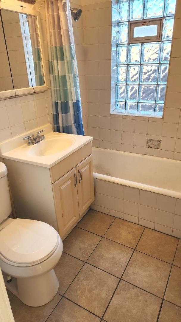 full bathroom with tile patterned floors, vanity, shower / tub combo, and toilet