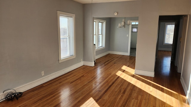 empty room with plenty of natural light and dark wood-type flooring