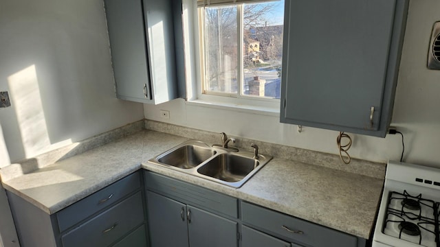 kitchen featuring gray cabinets, sink, and range