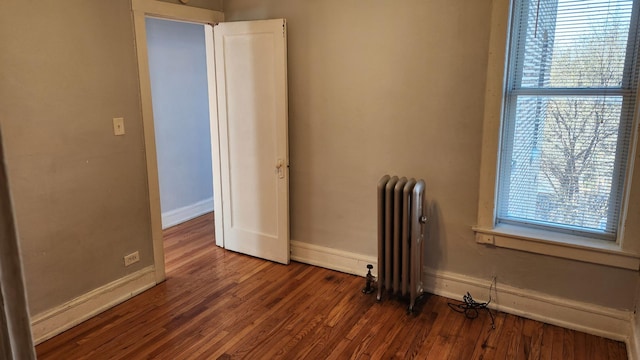 empty room featuring dark hardwood / wood-style flooring, radiator heating unit, and plenty of natural light