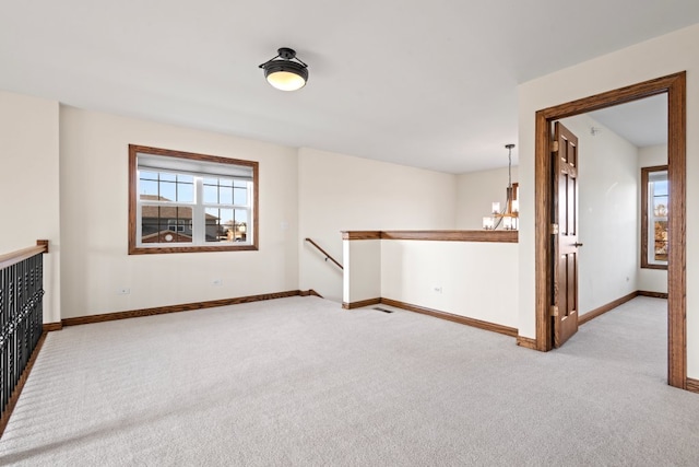 carpeted empty room featuring a chandelier