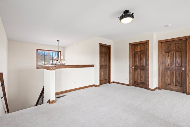 carpeted empty room with an inviting chandelier