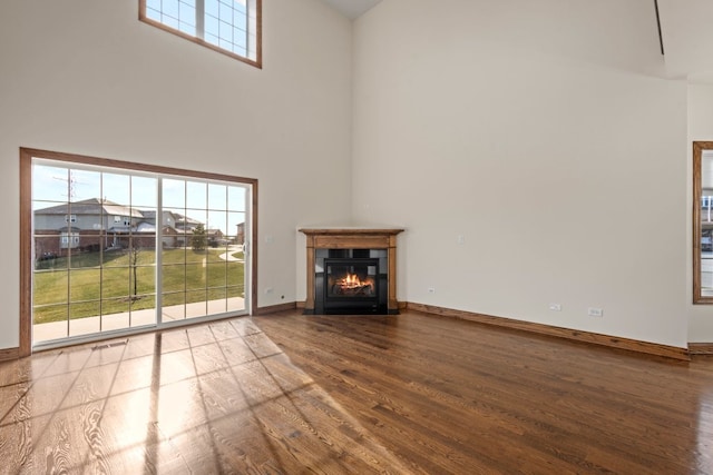 unfurnished living room with a towering ceiling and hardwood / wood-style flooring