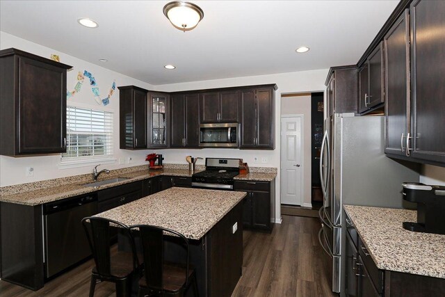 kitchen featuring sink, dark brown cabinets, appliances with stainless steel finishes, dark hardwood / wood-style floors, and light stone countertops