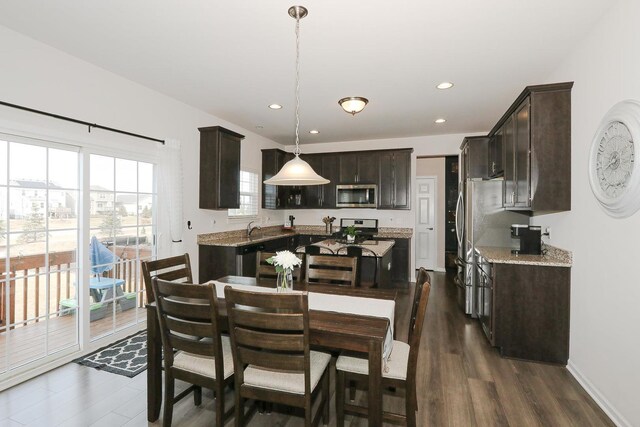 kitchen featuring ceiling fan, stainless steel appliances, dark hardwood / wood-style floors, a center island, and dark brown cabinetry