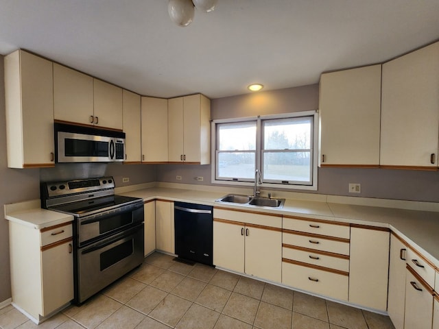 kitchen featuring sink, light tile patterned floors, cream cabinetry, and appliances with stainless steel finishes