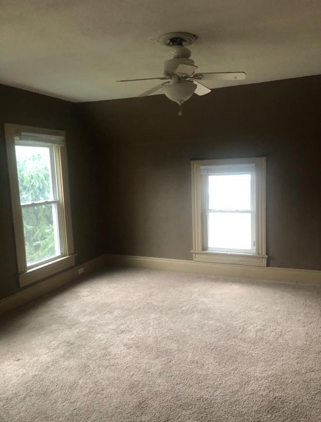 carpeted spare room with ceiling fan and a healthy amount of sunlight