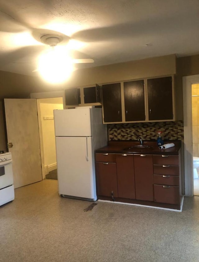 kitchen featuring tasteful backsplash, dark brown cabinetry, sink, and white appliances