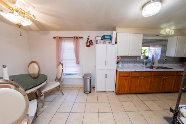 kitchen with tasteful backsplash, ceiling fan, sink, light tile patterned floors, and white cabinets