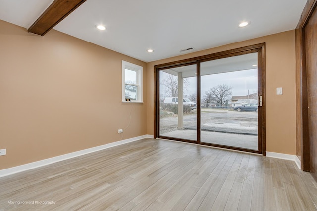 empty room featuring beam ceiling and light hardwood / wood-style floors