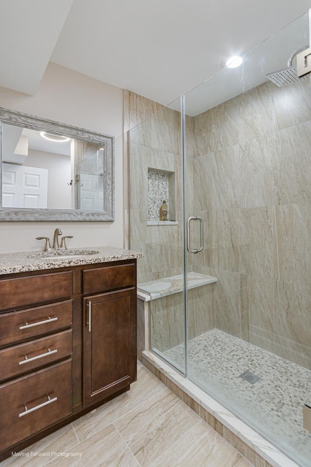 bathroom with vanity, an enclosed shower, and tile walls