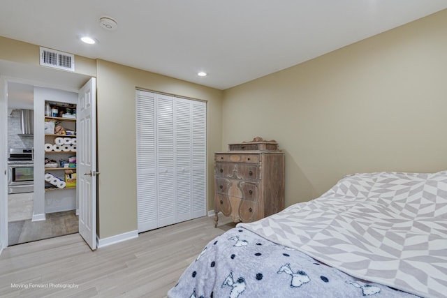 bedroom with light hardwood / wood-style floors and a closet