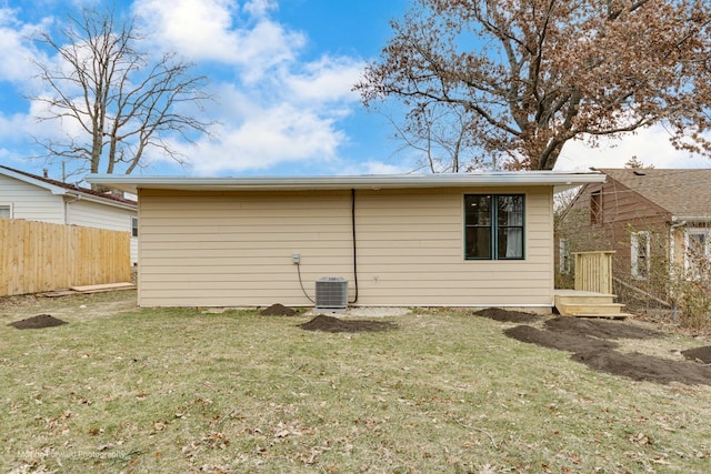 back of property with a yard and central AC