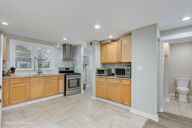 kitchen featuring light stone countertops, backsplash, stainless steel appliances, and wall chimney exhaust hood