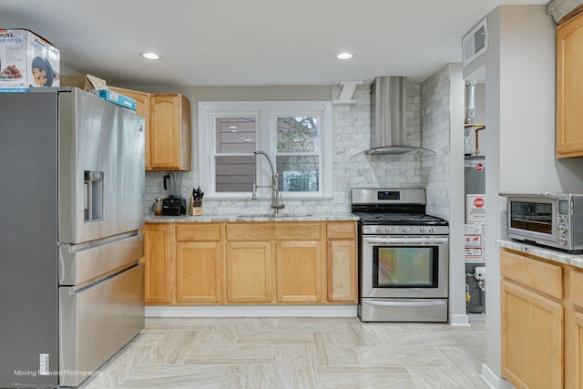 kitchen with decorative backsplash, light brown cabinetry, stainless steel appliances, sink, and wall chimney range hood