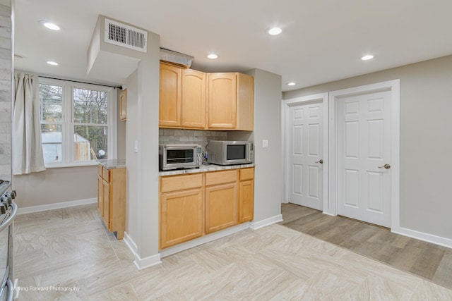 kitchen featuring light stone countertops, light brown cabinetry, backsplash, and light hardwood / wood-style floors