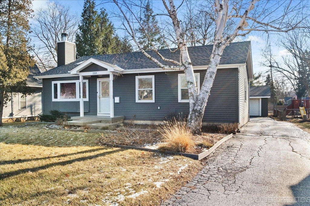 view of front of property featuring a garage, an outbuilding, and a front yard