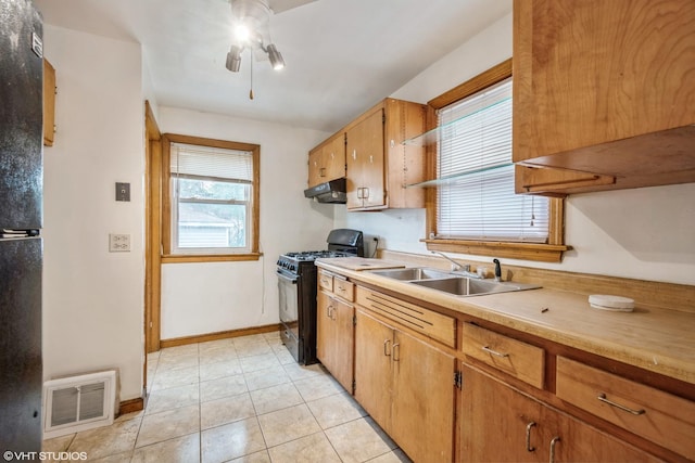 kitchen featuring black gas range, ceiling fan, sink, and light tile patterned floors