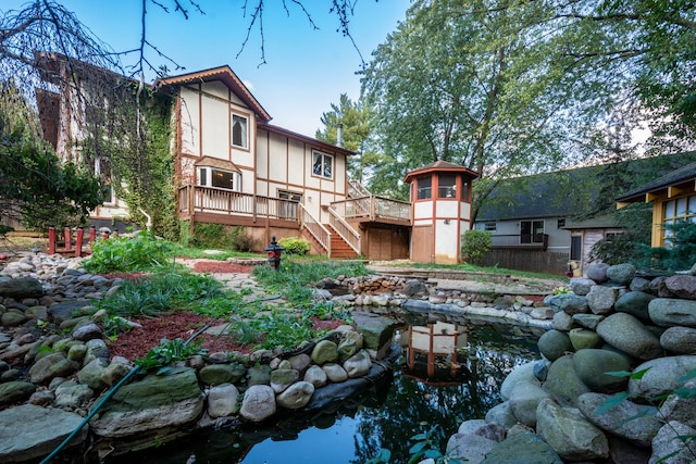 back of property featuring a garden pond and a deck