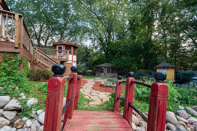 view of yard with a deck, a shed, and an outdoor fire pit