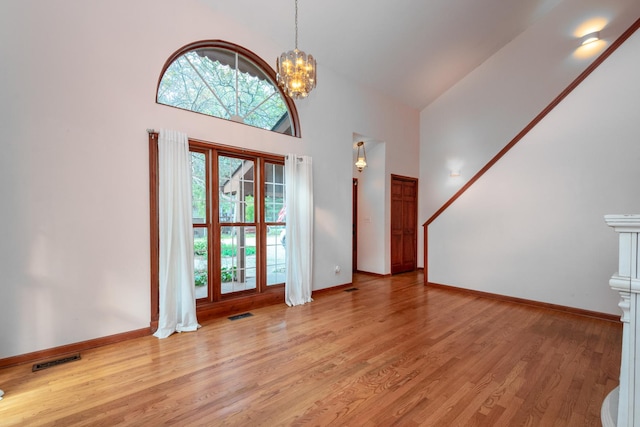 entrance foyer with a towering ceiling, light hardwood / wood-style floors, and a chandelier