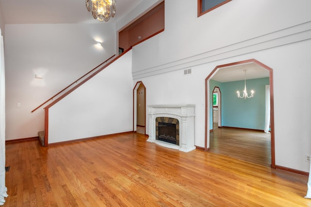 unfurnished living room featuring hardwood / wood-style flooring, a high ceiling, and a notable chandelier