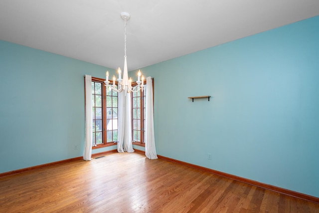 unfurnished room with an inviting chandelier and light hardwood / wood-style floors