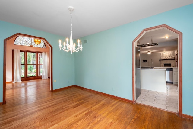 spare room featuring a chandelier and light hardwood / wood-style floors