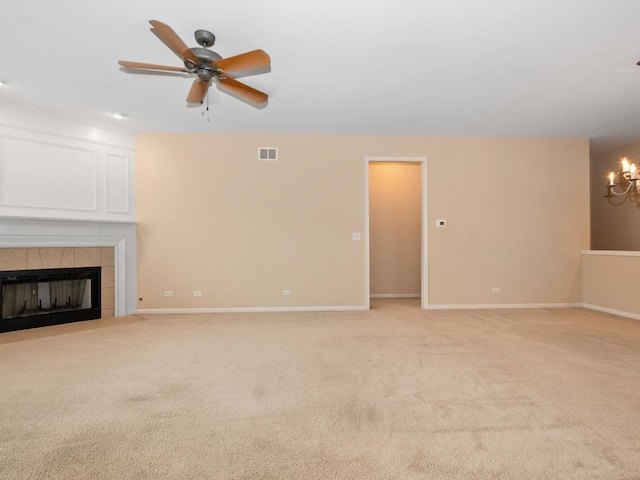 unfurnished living room featuring ceiling fan with notable chandelier, a fireplace, and light colored carpet