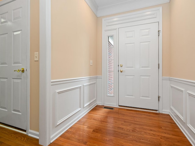 entryway with ornamental molding and light hardwood / wood-style floors