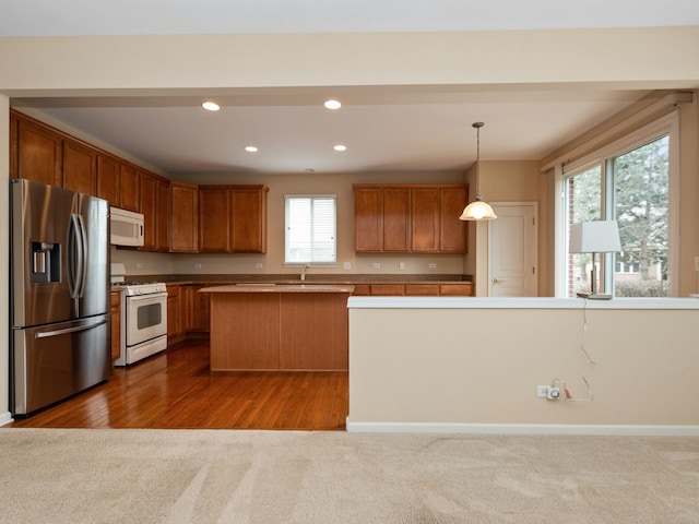 kitchen with pendant lighting, sink, white appliances, a kitchen island, and dark carpet