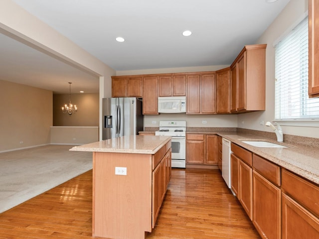 kitchen with sink, a chandelier, a center island, hanging light fixtures, and white appliances