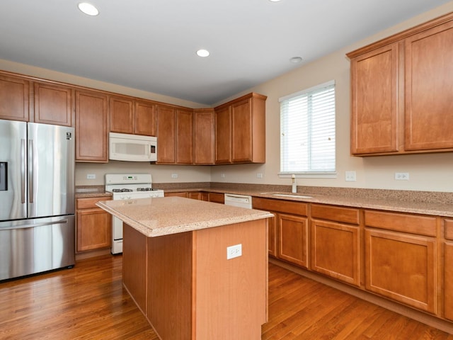 kitchen with white appliances, wood-type flooring, sink, and a kitchen island