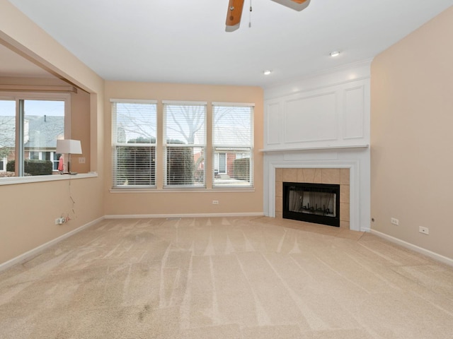 unfurnished living room featuring plenty of natural light, light colored carpet, a tile fireplace, and ceiling fan