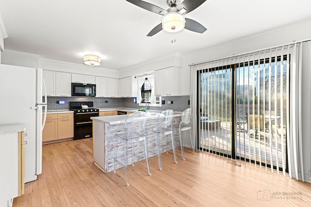 kitchen featuring a wealth of natural light, black appliances, kitchen peninsula, and white cabinets