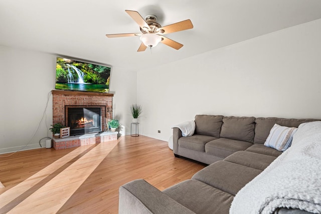 living room featuring hardwood / wood-style flooring, a brick fireplace, and ceiling fan