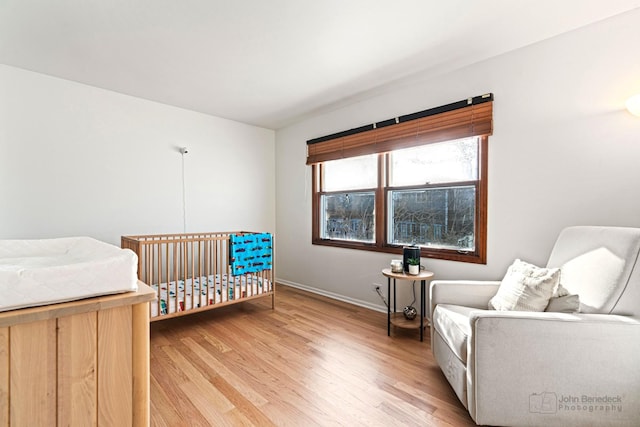 bedroom with a crib and light wood-type flooring