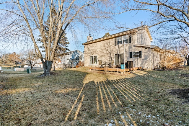 back of property with a wooden deck and a lawn