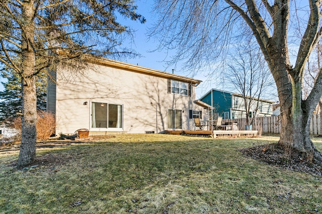 rear view of property featuring a wooden deck and a lawn