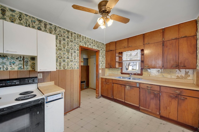 kitchen featuring white range with electric cooktop, ceiling fan, sink, and wood walls