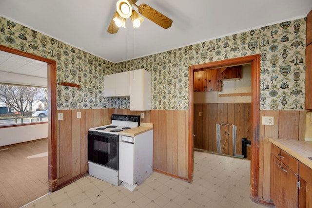 kitchen featuring white range with electric stovetop, ceiling fan, and wood walls