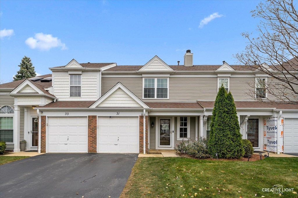 multi unit property featuring a garage and a front lawn