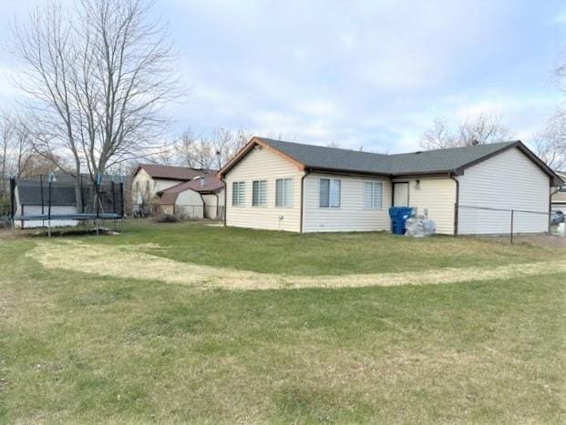 view of side of home with a trampoline and a lawn