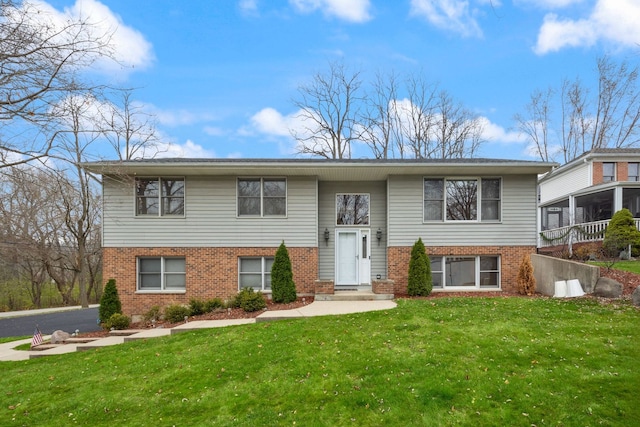 split foyer home featuring a front yard and brick siding