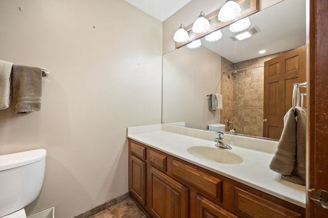 bathroom featuring toilet, visible vents, vanity, baseboards, and walk in shower